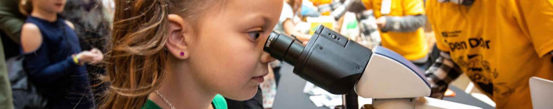 Child staring through a microscope
