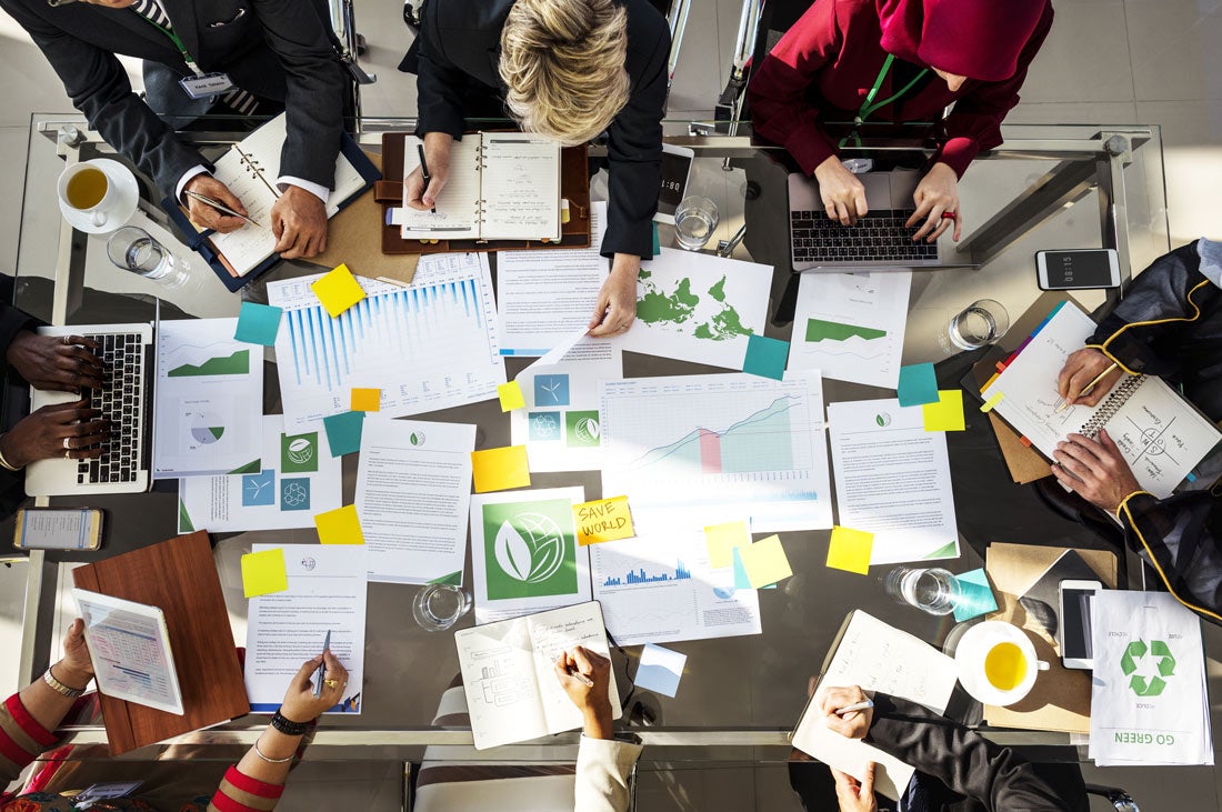 Papers on a desk with people sitting around