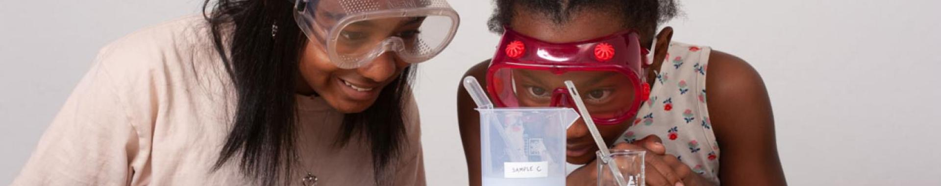 Two kids staring at a beaker with a pipette in it